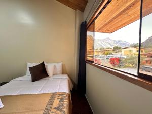 een slaapkamer met een bed en een groot raam bij Andher Palace Hotel in Ollantaytambo