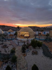 Una tienda de campaña en un desierto con una puesta de sol de fondo en Jabal shams domes, en Sa‘ab Banī Khamīs