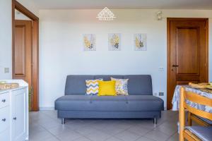 a blue couch in a living room with yellow pillows at Casa Torre di Nora - Morada in Pula