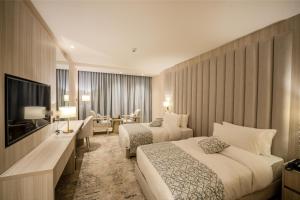 ein Hotelzimmer mit zwei Betten und einem Fernseher in der Unterkunft Petra Pillars Luxury Hotel in Petra