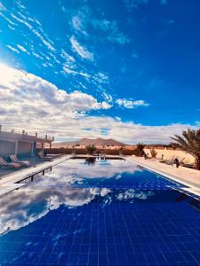 una piscina in mezzo al deserto di Hotel Camping Les Roses Des Dunes & Piscine a Merzouga