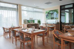 a restaurant with wooden tables and chairs and windows at Reichels Parkhotel in Bad Windsheim