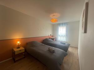 two beds in a room with a lamp on a table at Le Grand Viennois Futuroscope in Jaunay-Marigny