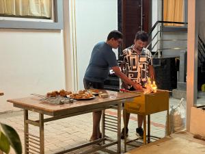 Dos hombres están preparando comida en una mesa. en Yelagiris Honey Stay, en Yelagiri