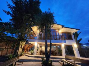 ein großes weißes Haus mit Balkon und Bänken in der Unterkunft Rimtara Nan ริมธารา น่าน in Ban Khia