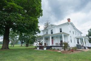 a white house with a tree in the yard at Old Furnace Inn in Harrisonburg