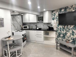 a kitchen with white cabinets and a table and a tv at Modern 3-bed Serviced Appartement - Milnsbridge in Lindley +14 photos