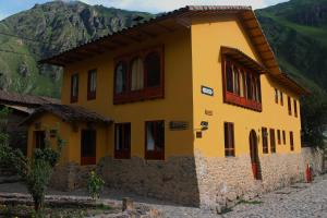 a yellow house with mountains in the background at SAUCE Hotel Boutique in Ollantaytambo