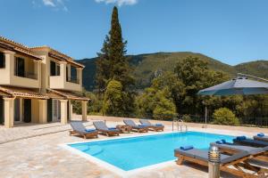 a villa with a swimming pool with chairs and an umbrella at Elite Villa Dio in Áno Korakiána
