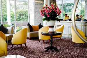 a lobby with yellow chairs and a vase of flowers on a table at Astanaraya Suites Hotel in Jakarta