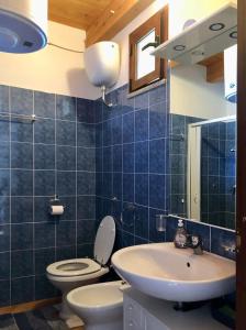a blue tiled bathroom with a toilet and a sink at Casa relax Nasiu in Perdaxius