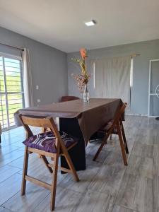 een eettafel met stoelen en een vaas met bloemen bij Entre Sierras Cabañas in Tanti +8 foto's