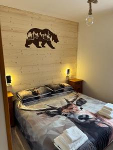 Dolomiti Dream House في سنسنيجا: غرفة نوم بسرير كبير مع وجود دب على الحائط