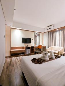 una camera d'albergo con un letto e una TV a schermo piatto di Astanaraya Suites Hotel a Giacarta