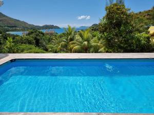 a blue swimming pool with a view of the ocean at Mirella Villa in Praslin