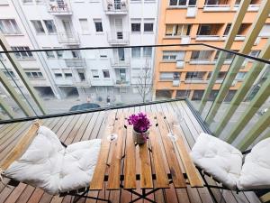 Cosy Terrace Studio close to city center-Limp11 في لوكسمبورغ: شرفة زجاجية عليها طاولة خشبية عليها زهور