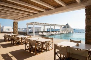 an outdoor patio with tables and chairs and a pool at Porto Mykonos in Mikonos