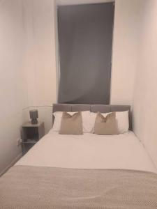 un dormitorio con una cama con sábanas y almohadas blancas en Two bedroom close to city, en Sunderland