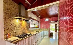 a kitchen with a stove and a red brick wall at Alfa Serra lago e montanha in Guapimirim