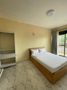 a bedroom with a bed and a large window at Exactly one minute away from Victoria Mall in Entebbe
