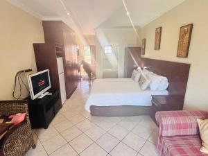 Un dormitorio con una cama, un televisor y un sofá. en Ocean View Villas B09, en Port Edward 32 fotos más