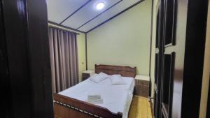 una piccola camera da letto con un letto con lenzuola e cuscini bianchi di Hotel Yaşıl Park a Mekhrably