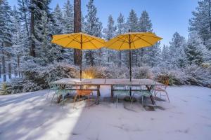 un tavolo e sedie con ombrelloni gialli nella neve di Star Haven Game Room & Forest Views a Truckee