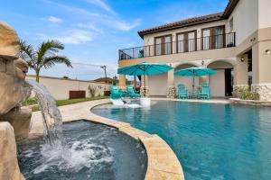 a swimming pool with a fountain in front of a house at Paradise Villa: 2 blocks from beach, private pool in South Padre Island