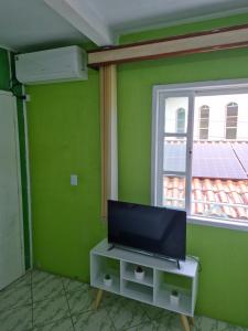 a tv on a cabinet in a room with a window at Casa em Ganchos in Governador Celso Ramos