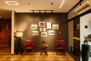 a waiting room with red chairs and pictures on the wall at Hotel Ferraz in Pouso Alegre