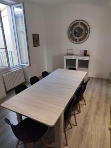 Duplex spacieux et lumineux en centre-ville في شاتودون: طاولة خشبية كبيرة مع كراسي في غرفة بها ساعة +20 صورة