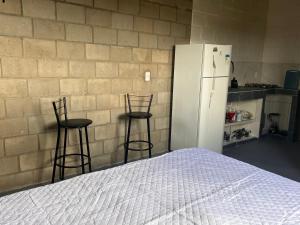 um quarto com uma cama, dois bancos altos e uma geladeira em Raizes do bem estar em Lucena
