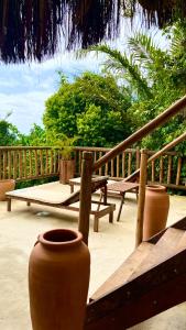 a patio with two large vases and a bench at Eliza, Bangalô vista mar em Trancoso in Trancoso