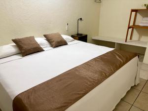 a large white bed with brown pillows on it at Casa Leon Rinconada in Puerto Escondido