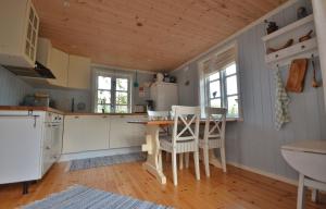 a kitchen with a wooden ceiling and a table and chairs at Rabben Feriested in Lyngværet