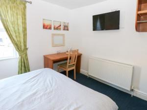 een slaapkamer met een bed, een bureau en een televisie bij Bedroom 2 in Wolsingham