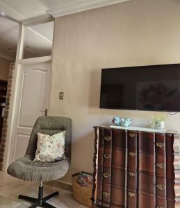 una camera con sedia e televisore appeso a un muro di Goedehoop a Somerset West