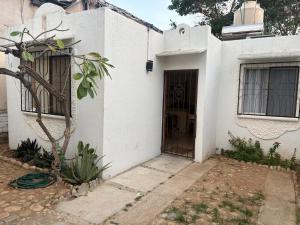 a white house with a door and a tree at Casa Leon Rinconada in Puerto Escondido