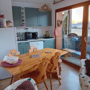 cocina con mesa y mesa de madera con sillas en Location T2 30m2 superdévoluy, en Le Dévoluy