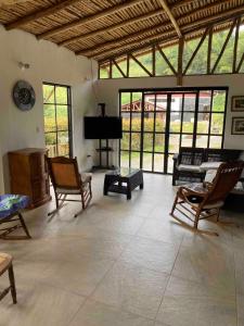 a living room with rocking chairs and a piano at Finca El Cural in Sasaima