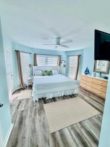 a bedroom with a white bed and a flat screen tv at Saltwater Solace For 8 in Galveston