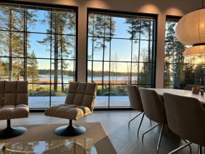 een eetkamer met een tafel en stoelen en grote ramen bij New Seaside Villa with Beach Sauna and Panoramic Views in Porvoo