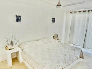 プエルト・モレロスにあるCasa Amor Pto Morelosの白いベッドルーム(ベッド1台、テーブル付)