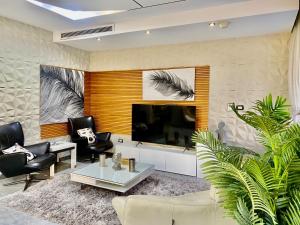 a living room with a flat screen tv and black chairs at Spacious Luxury 5BR Villa with Private Pool near GEM in Kafr Ghaţāţī
