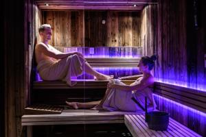 two women sitting on benches in a room with purple lights at Haus Melisande in Sölden