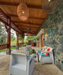 un patio con sedie in vimini e un muro in pietra di Villa refugio de paz a Bayaguana
