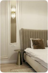 a bedroom with a bed with a table and a chandelier at Vanilla Studio in Timişoara