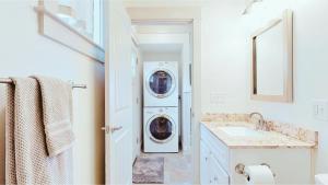 een badkamer met een wasmachine en droger naast een wastafel bij Tidal House in Surfside +100 foto's