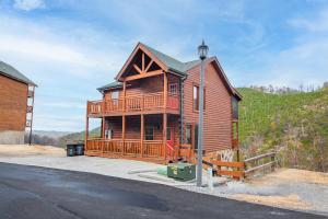 uma grande cabana de madeira com varanda e poste de luz em Splash Mountain Lodge By Avada Properties em Little Cove