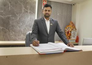 a man in a suit sitting at a desk with a book at Hotel Mountain Bliss' New Delhi City center in New Delhi
